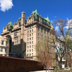 Hotel Fort Garry in Winnipeg, historic stone building with green-copper roofs under blue sky.