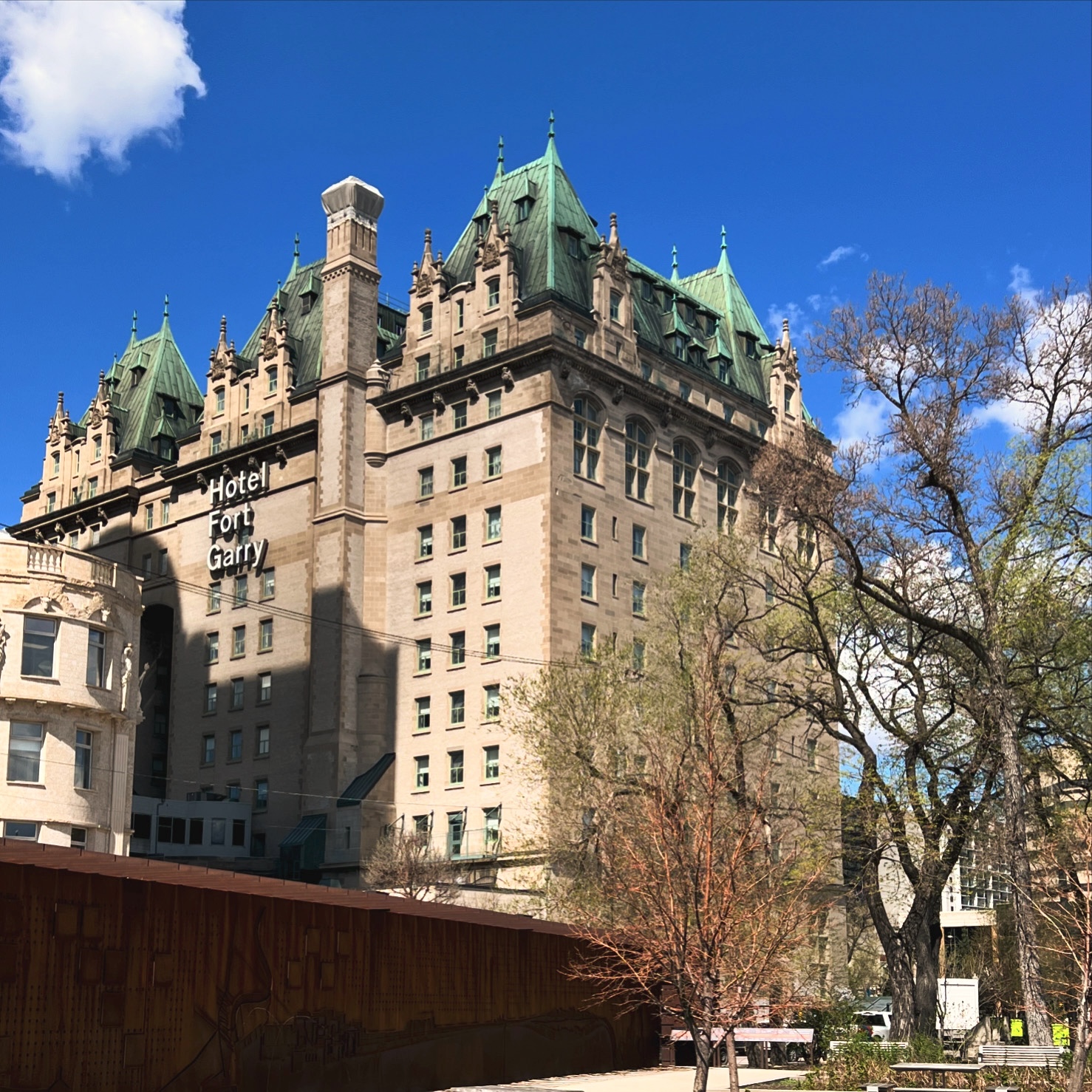 Hotel Fort Garry in Winnipeg, historic stone building with green-copper roofs under blue sky.